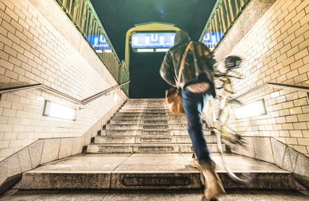 Blurred defocused man with bike going out from Rosa Luxemburg subway station in Berlin - Urban life travel concept with street guy at underground location by night - Grunge contrast filterのeditorial素材