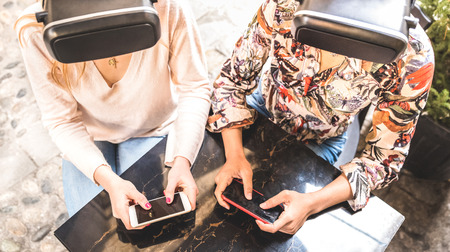 Girl friends playing on vr glasses outdoor - Virtual reality and wearable tech concept with young people having fun together with headset goggles - Generation z digital trends - Bright contrast filterの写真素材