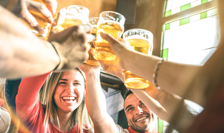Friends drinking and toasting beer at brewery bar restaurant - Friendship concept on young millenial people having fun together on happy hour at brew pub - Focus on girl face - Summer sunshine filterの写真素材