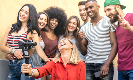 Multiracial young friends taking selfie with mobile smart phone and stabilizer gimbal - Friendship concept with millenial people having fun together sharing live feeds on social media networksの写真素材
