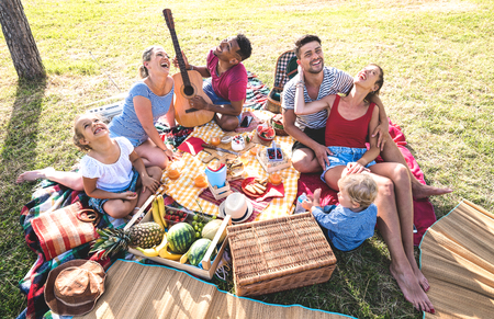 High angle top view of happy families having fun with kids at pic nic barbecue party - Multiracial love concept with mixed race people playing with children at public park - Warm retro vintage filter