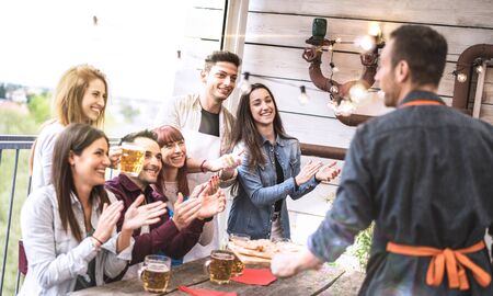 Young friends having fun drinking beer on balcony at house dinner party - Happy people eating pizza at fancy alternative restaurant together - Dining lifestyle concept on bright sunshine filterの写真素材
