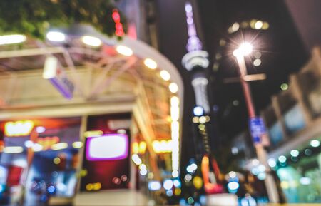 Blurred defocused view of urban nightscape at city center in Auckland capital of New Zealand - Abstract bokeh background by night with glowing lights and blurry buildings - Vivid colors filterの写真素材