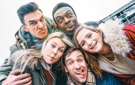 Multiracial best friends taking selfie outdoor on autumn winter clothes - Happy youth concept with...