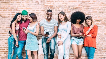 Happy multiethnic friends using smartphone at university college backyard - Young people on addict mood with mobile smart phone - Technology concept with always connected millennials - Filter imageの写真素材
