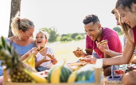 Cropped view of happy multiracial families having fun with kids at pic nic barbecue party - Multiethnic love concept with mixed race people eating with children at public park - Warm vivid filterの写真素材