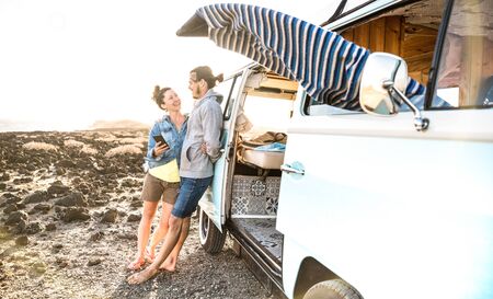 Young hipster couple at relax moment together by oldtimer mini van - Travel lifestyle concept with...