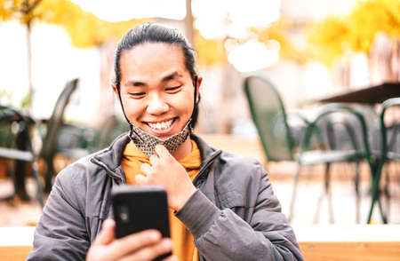 Happy asian guy smiling with open face mask after lockdown reopening - New normal lifestyle concept...