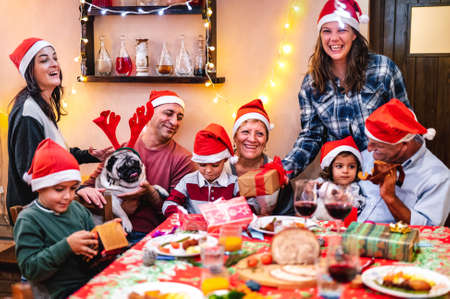 Multi generation family having fun at christmas diner feast - Winter holiday x mas concept with parents and children eating together opening presents at home - Focus on middle frame - Warm filterの写真素材
