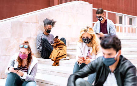 Urban milenial students using smart phones with face mask on Covid second wave - Serious guys and...