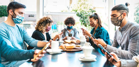 People using mobile smart phones at coffee bar - New normal gathering concept about bored friends...