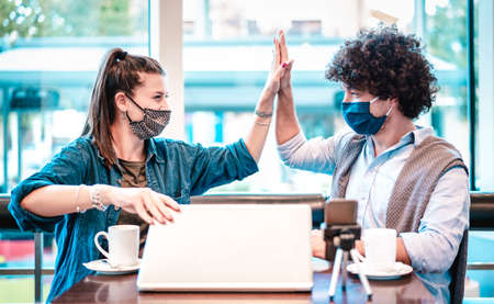 Young milenial influencers at coworking space with facemask - New normal marketing concept with next...