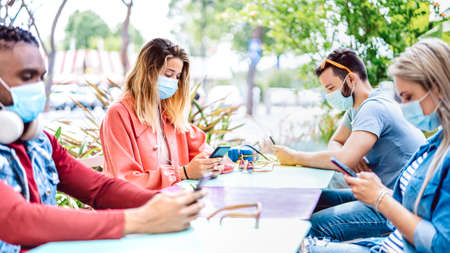 Worried friends group using tracking app on mobile smart phone - Milenial people sharing content by social media network - New normal social distancing concept - Bright filter with focus on left womanの写真素材