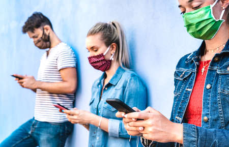 Milenial friends using mobile phone covered by face mask - Young people sharing content on cellphone...
