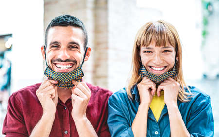 Happy couple in love smiling with open face mask - New normal lifestyle and relationship concept...