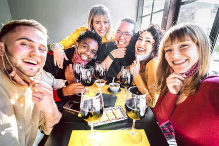 Friends taking selfie at winery with open face mask - People having fun together drinking red wine...