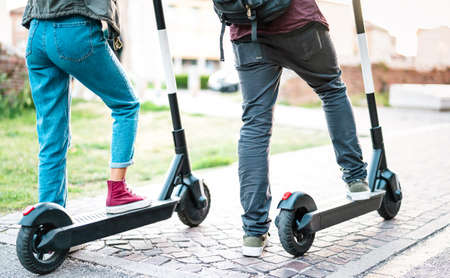 Close up of city commuters using electric scooter at urban park - Millenial students riding new modern ecological mean of transport - Green eco energy concept with zero emission - Bright retro filterの写真素材