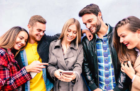 Milenial friends on fun moment using mobile smart phone - Young people always connected at social media devices - Technology concept with modern teenagers sharing content online - Bright vivid filterの写真素材