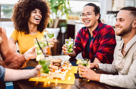 Young friends toasting mojito drinks at fashion cocktail pub restaurant - Life style concept with...