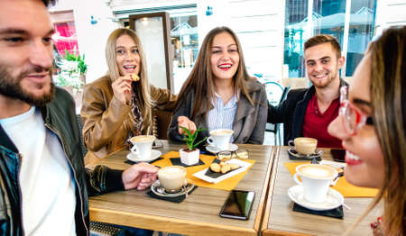 People group drinking cappuccino at coffee bar restaurant - Young friends having fun together at outdoor cafeteria - Friendship concept with happy guys and girls at sidewalk cafe  - Warm vivid filterの写真素材