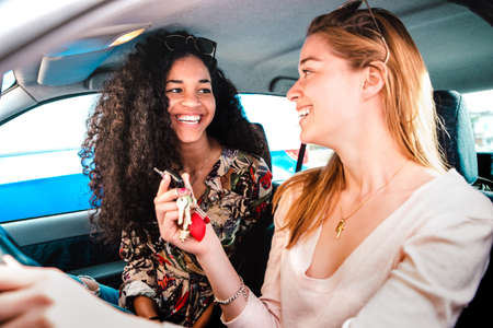 Happy female best friends having fun at car roadtrip - Transportation concept and urban ordinary life with young women girlfriends at happy travel vacation moment on the road - Bright vivid filterの写真素材