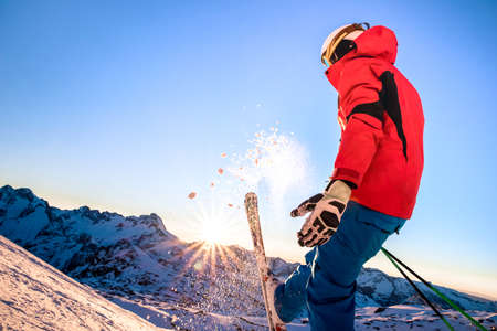 Professional skier at sunset on relax moment in french alps ski resort - Winter sport concept with adventure guy on mountain top ready to ride down - Side view point on vivid azure filterの写真素材