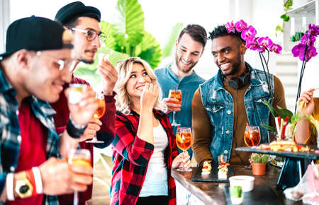 Multicultural friends group having fun at pre dinner party on aperitif buffet drinking cocktails and eating snacks - People life style concept on happy hour time together at home - Bright vivid filterの写真素材
