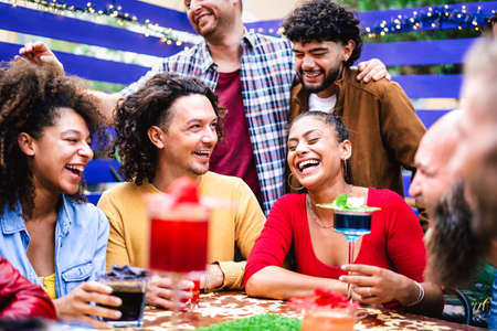 Multicultural people having genuine fun moment at fancy cocktail bar patio - Beverage life style concept with people laughing together on happy hour at sidewalk restaurant cafe - Bright vivid filterの写真素材