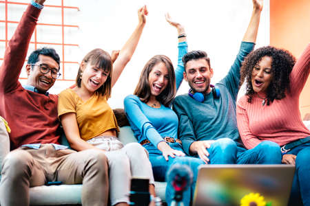 Young vloggers having fun on streaming platform with phone web cam - Social networking concept with milenial guys and girls sharing live vlog feeds on media networks at trendy coworking spaceの写真素材
