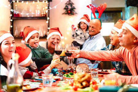 Big multi generation family toasting at christmas dinner feast - Winter holiday x mas concept with parents and children eating together at home supper reunion - Warm vivid filter with focus on glassesの写真素材