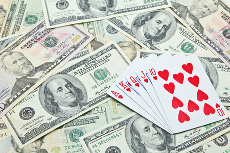 Playing cards on pile of US dollar banknotesの写真素材