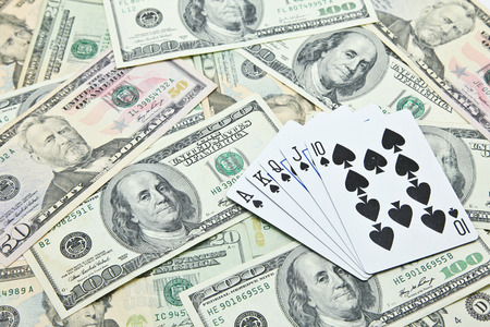 Playing cards on pile of US dollar banknotesの写真素材