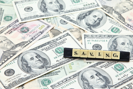 Word saving on pile of US dollar banknotesの写真素材