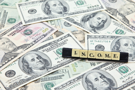 Word income on pile of US dollar banknotesの写真素材