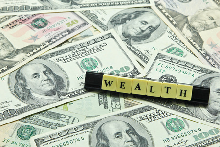 Word wealth on pile of US dollar banknotesの写真素材