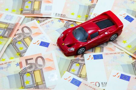 Red super car model on pile of 50 Euro banknotesの写真素材