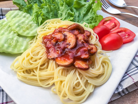 Spaghetti tomato sauce and mushroom with green oak and butter head on wooden table.の写真素材