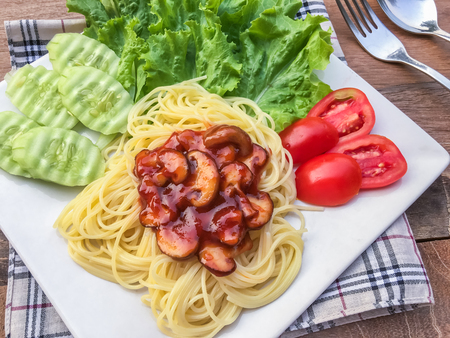 Spaghetti tomato sauce and mushroom with green oak and butter head on wooden table.の写真素材