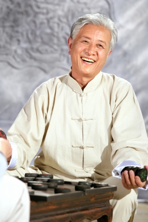 oriental senior adult playing chinese chessの写真素材