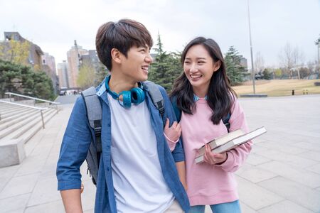 Two happy College students walking together and talking at campusの写真素材