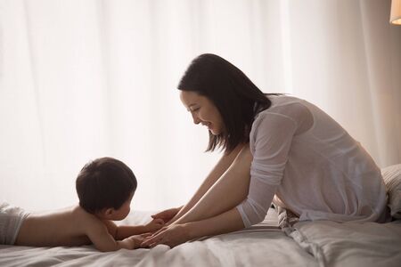 Mother playing with baby on bedの写真素材