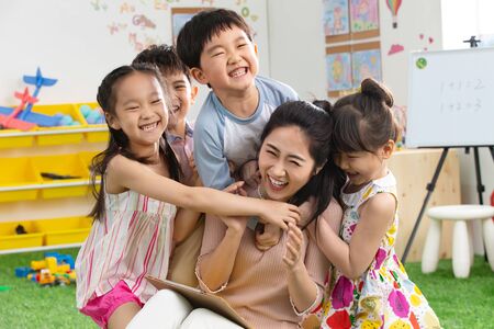 Kindergarten teachers and children embrace togetherの写真素材