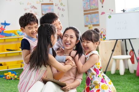Kindergarten teachers and children embrace togetherの写真素材