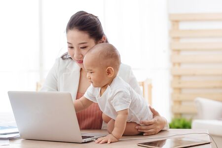 Young mother holding the children work at homeの写真素材