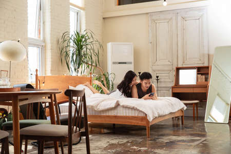 Young couple using mobile phone in bedroom at home. Lifestyle conceptの写真素材
