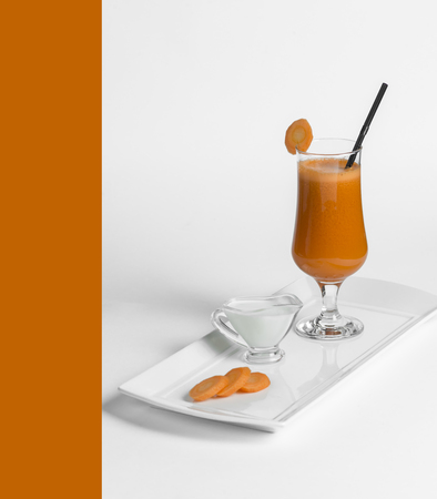 carrot fresh juice in a glass on a white plateの写真素材