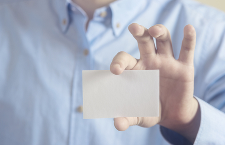 Close up hand of casual man holding white card on concrete wall backgroundの写真素材