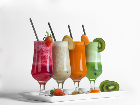 Strawberry, kiwi, carrot and banana smoothies with pieces of fruits on white backgroundの写真素材