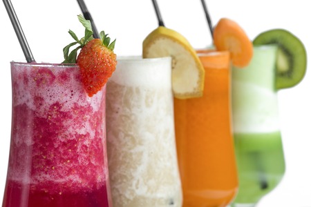 Strawberry, kiwi, carrot and banana smoothies with pieces of fruits on white backgroundの写真素材