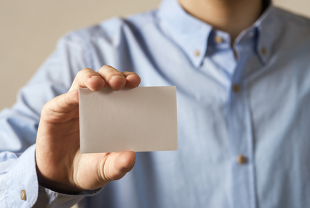 Close up hand of casual man holding white card on concrete wall backgroundの写真素材